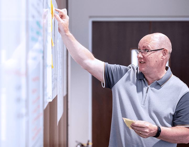 Founder Dai Griffiths placing post-it notes onto a whiteboard